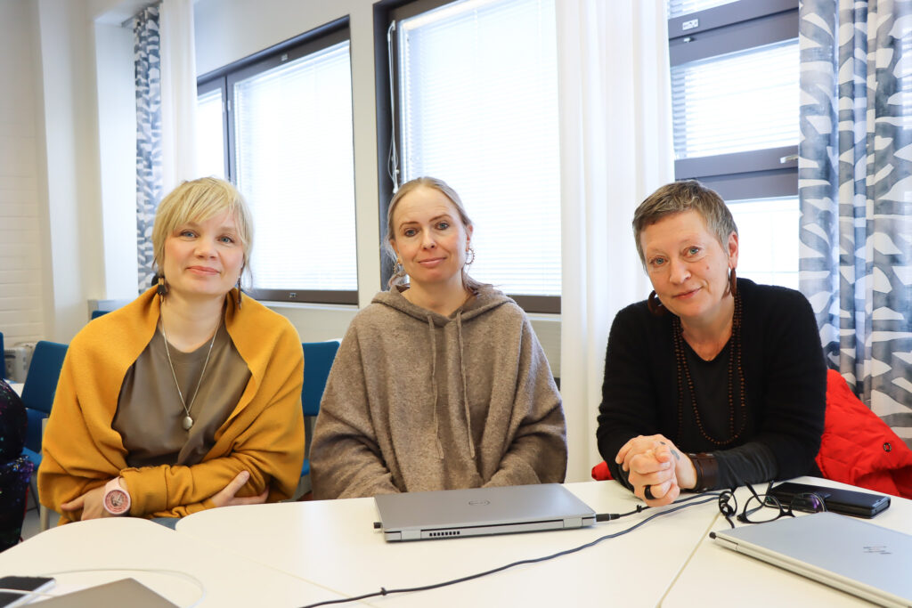 Vasemmalta oikealle THL:n työntekijät Noora Sipilä, Minna Ahola ja Helka Raivio istuvat pöydän ääressä.