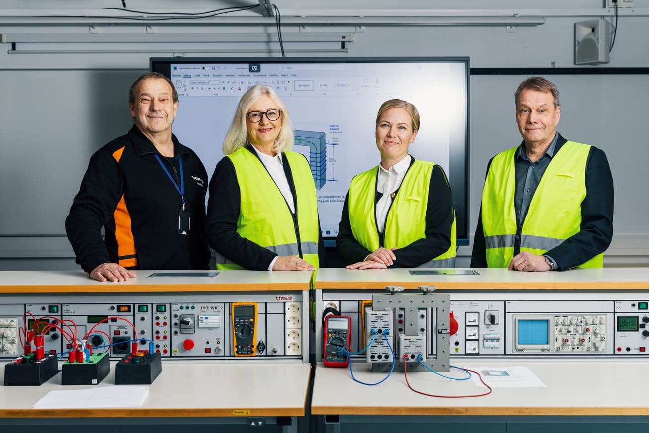 Kuvassa Vamian henkilökuntaa keltainen liivi päällä sähkön luokassa.