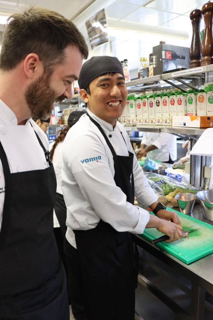 Barry Money in the kitchen speaking to a student