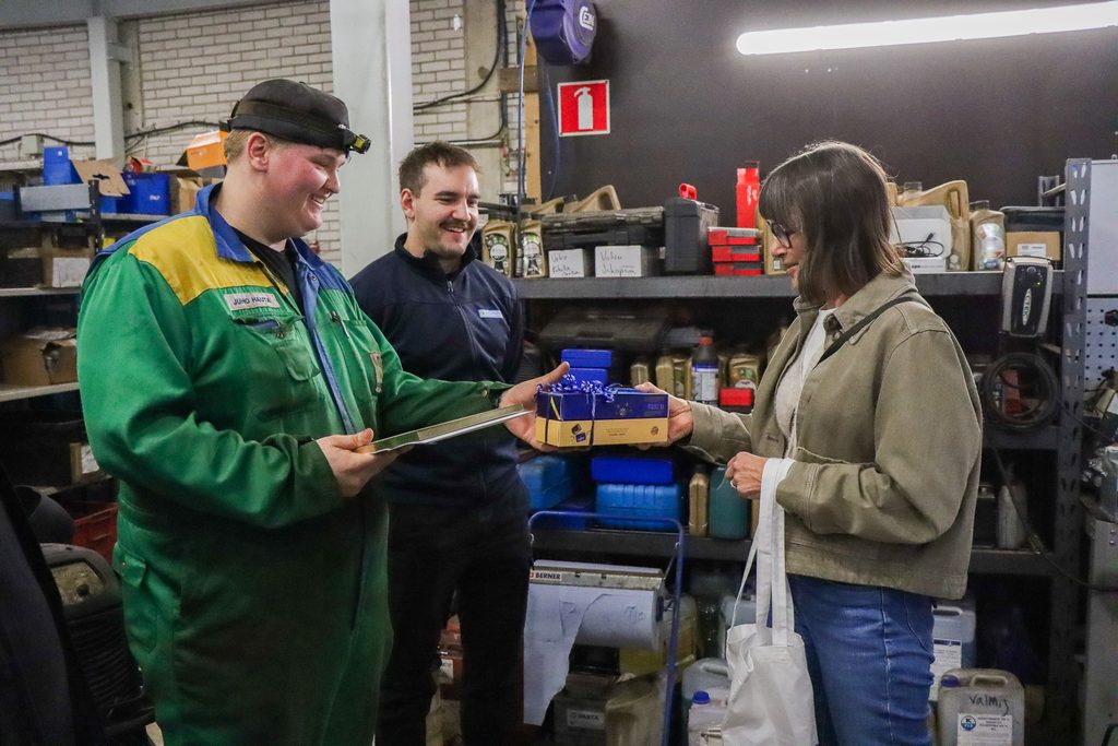 Koulutussuunnittelija ojentaa Juholle suklaarasiat, Juho pitelee kädessään diplomia ja hymyilee.
