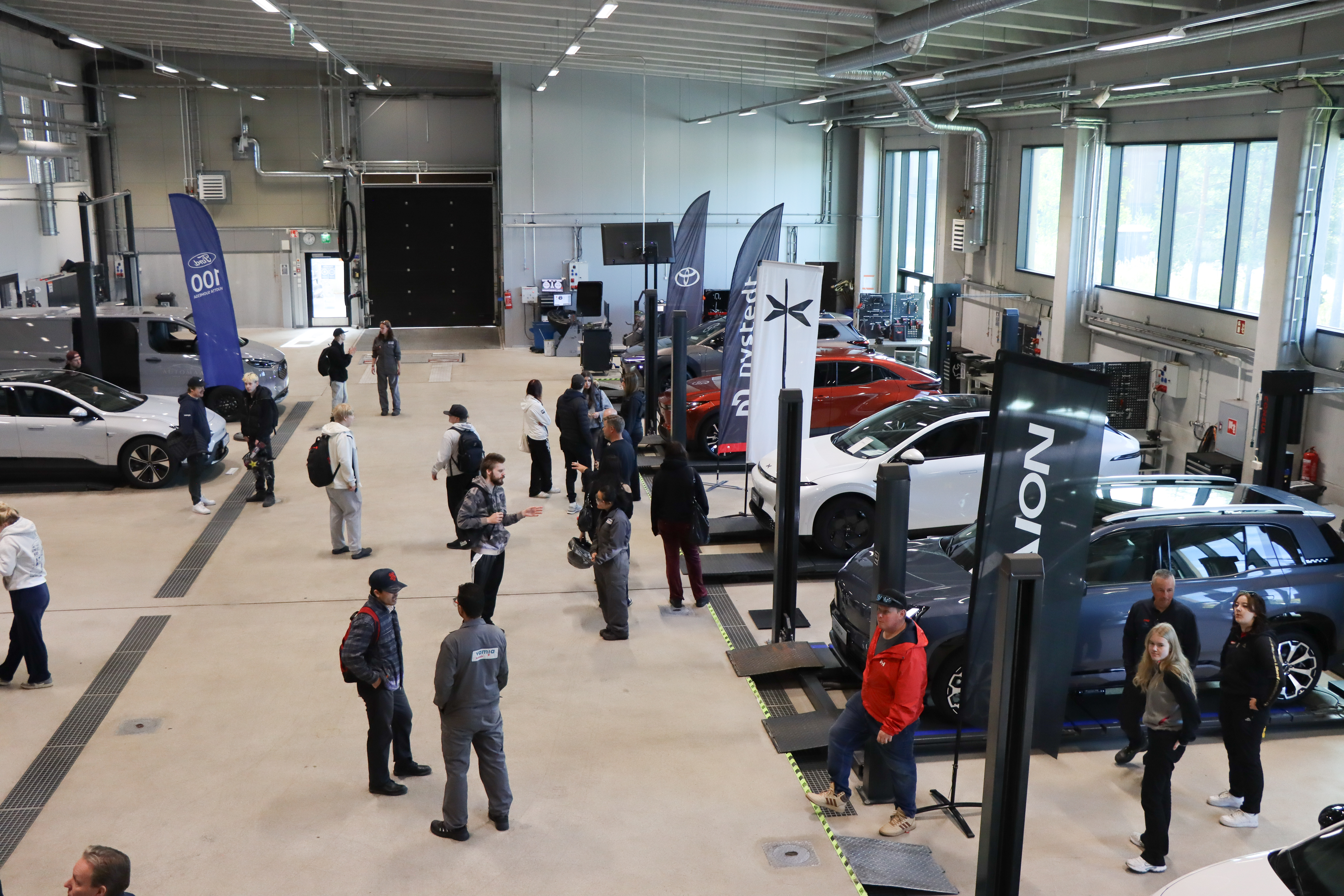 Vamian autohallissa tapahtumakävijät tutustuvat sähköautoihin.